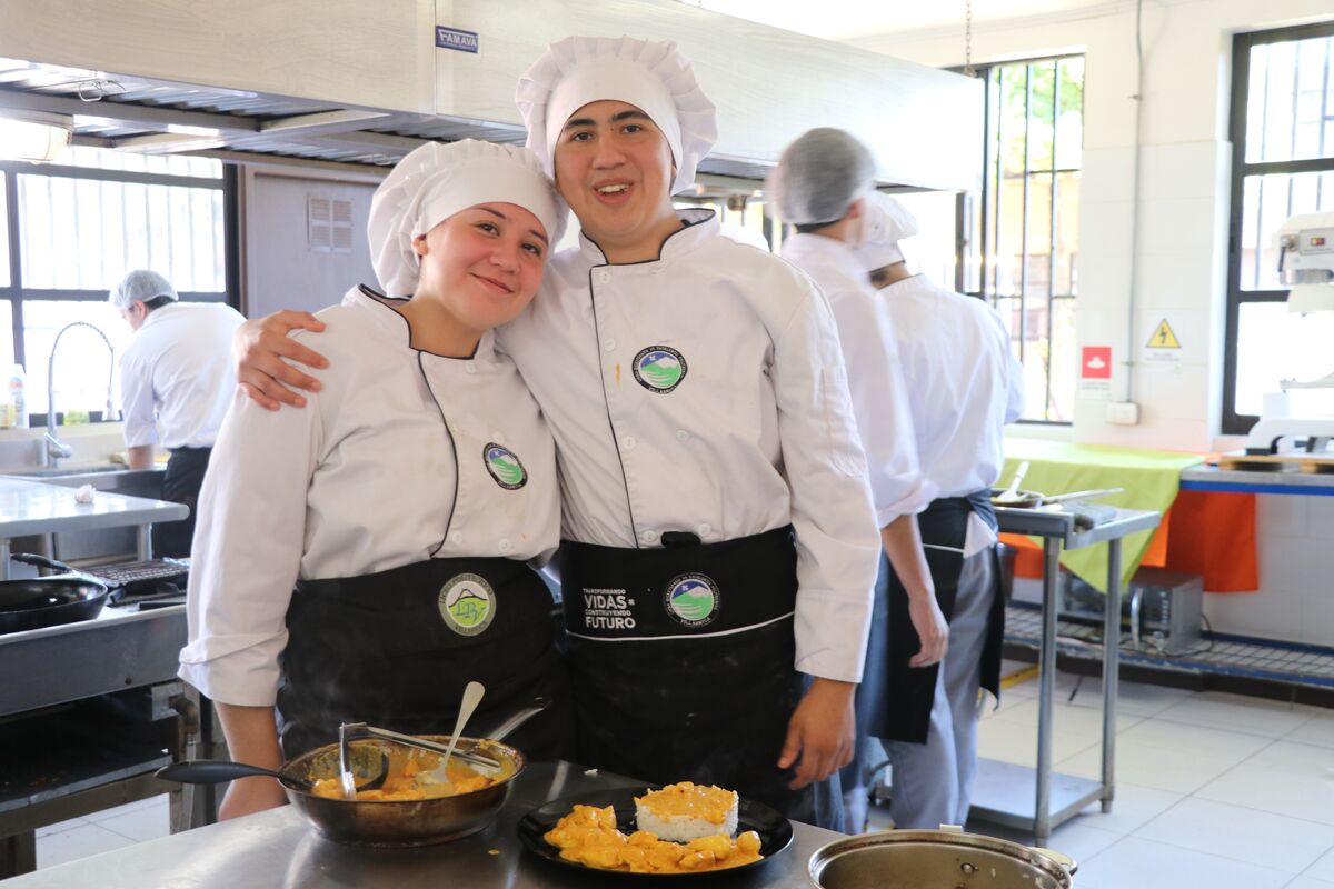 Estudiantes de gastronomía preparando un plato en el taller