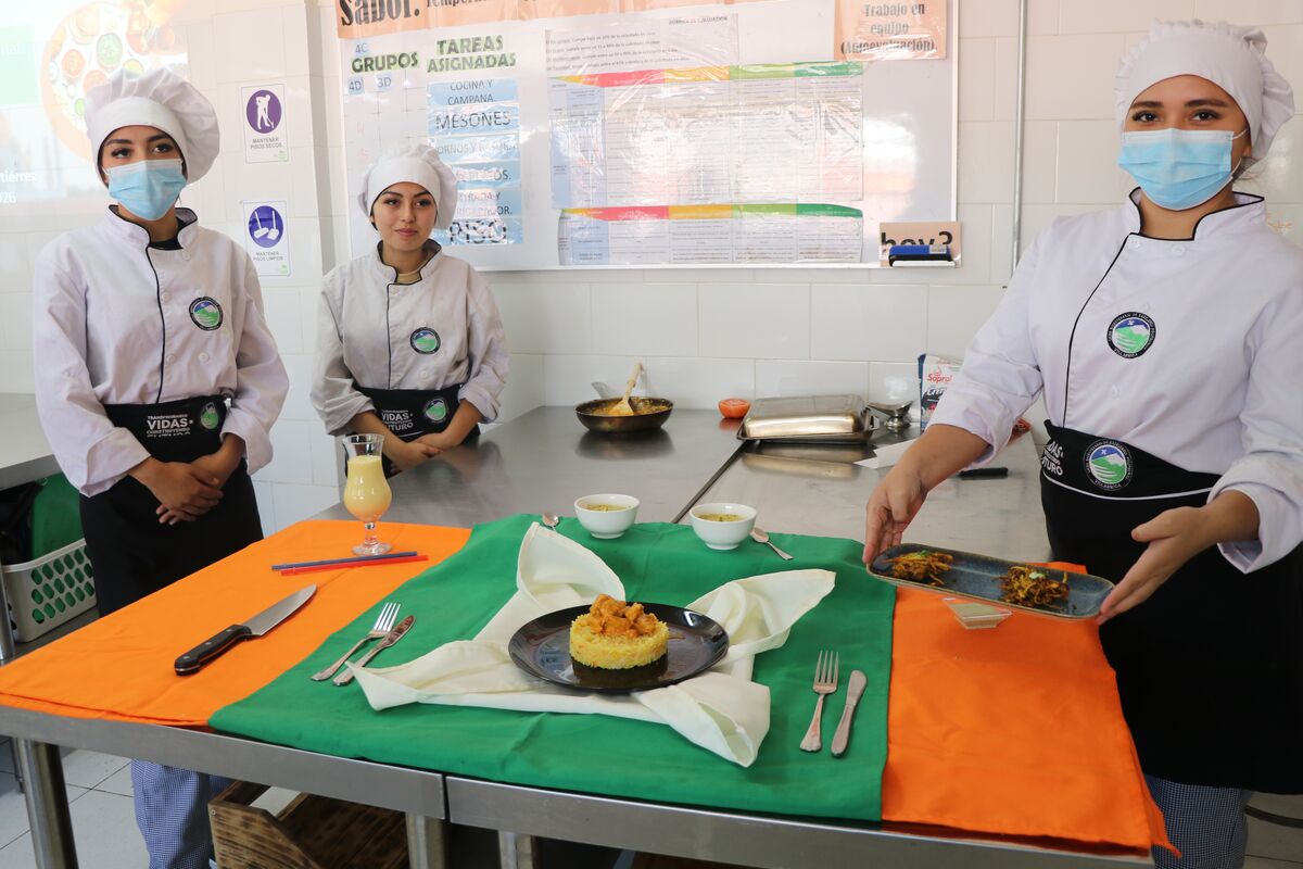 Estudiantes con uniforme de cocina junto a su preparación