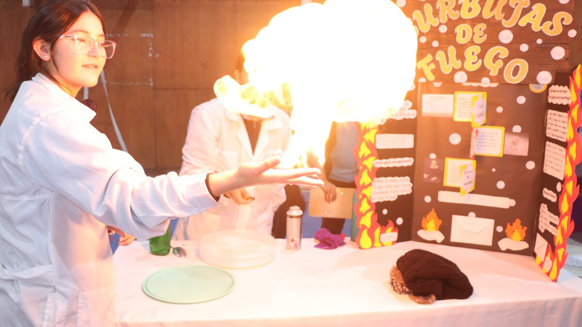 Estudiante realizando una demostración de química ante su curso